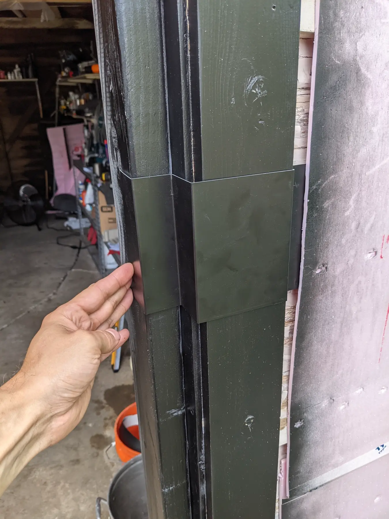 Dark custom flashing profile held against a matching building edge to check its fit.