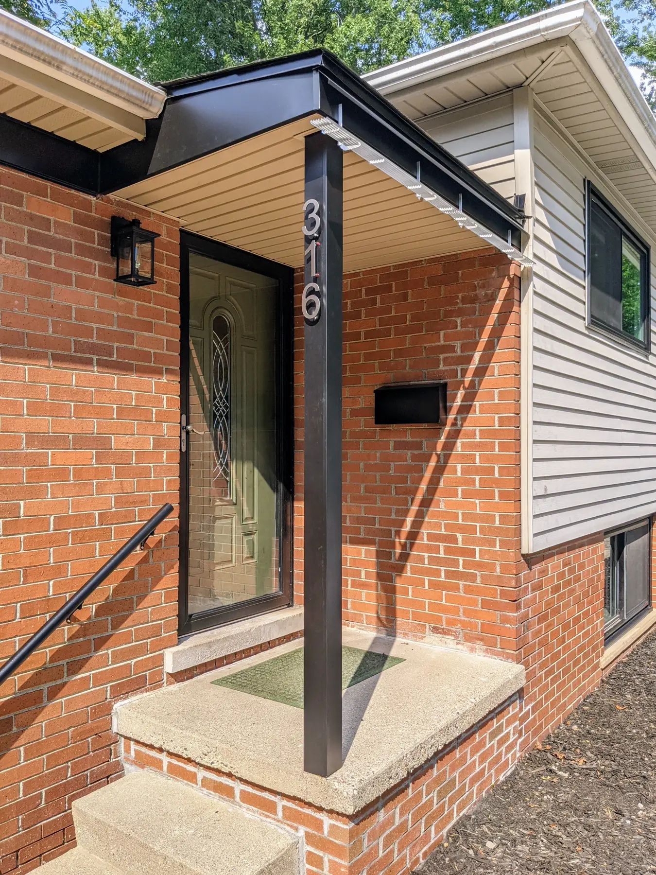 Completed entrance with dark custom aluminum flashing around the roof edge and support post.