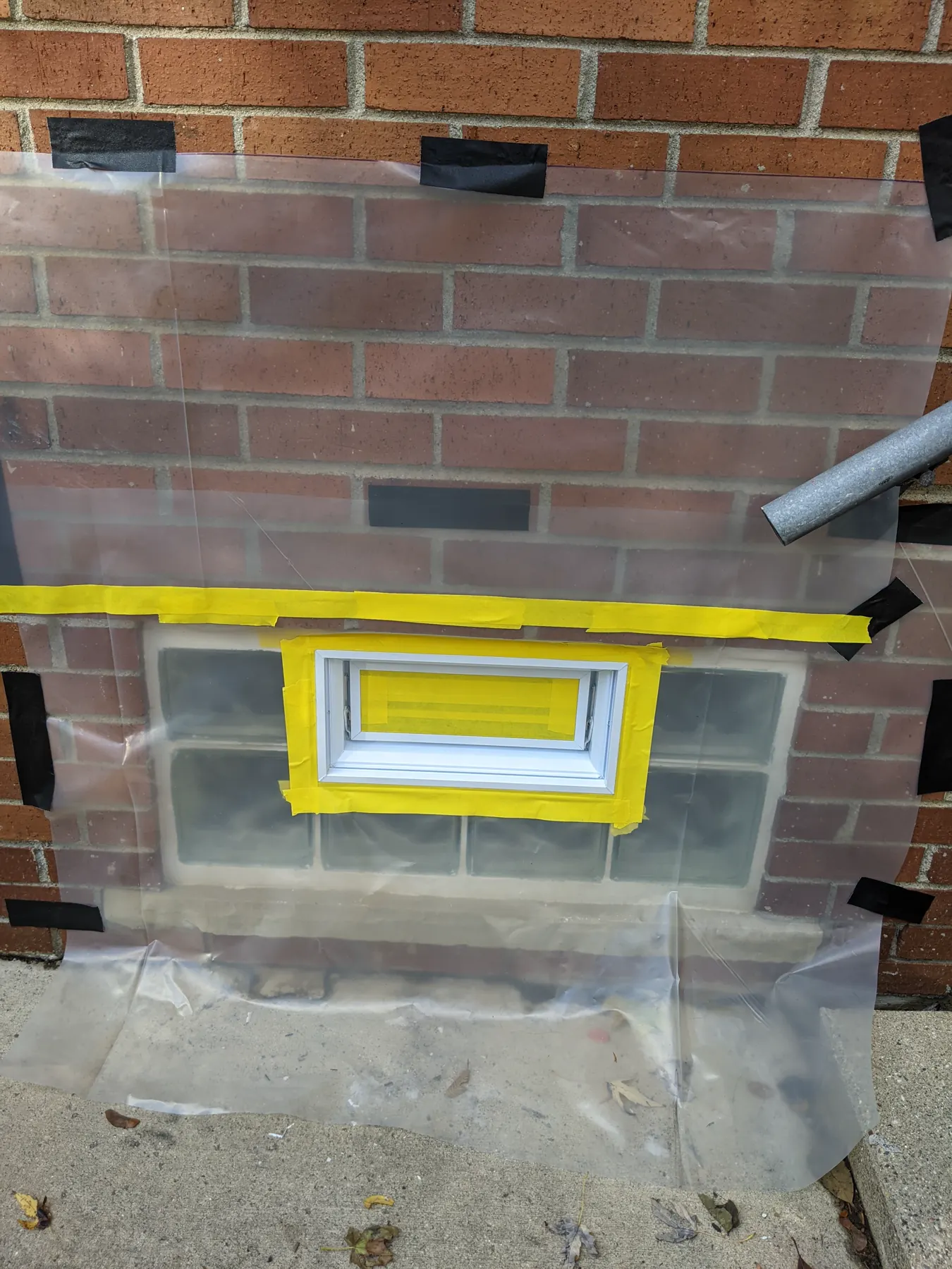 Close view of taped vent edges and plastic sheeting protecting the surrounding glass blocks and brick.