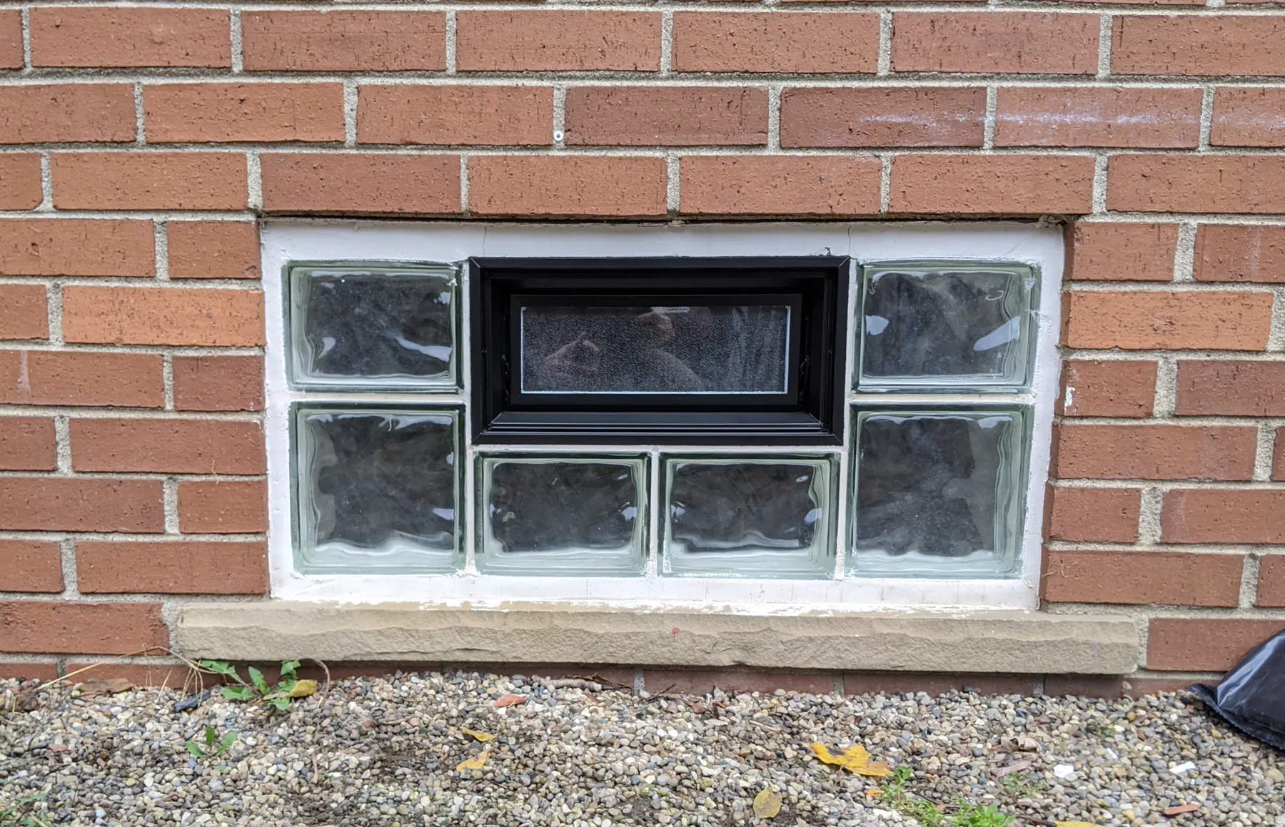 A second glass-block opening with its center vinyl vent finished in black.