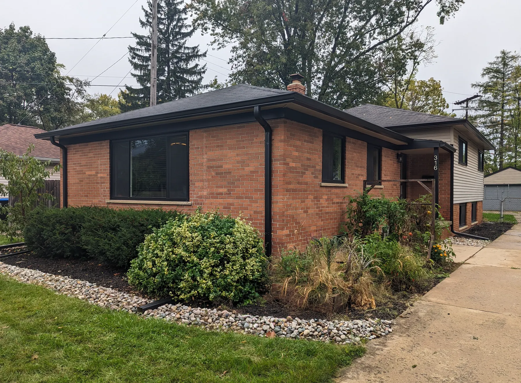 Whole brick house with coordinated black windows, roof flashing, gutters, downspouts, and basement vent frames.