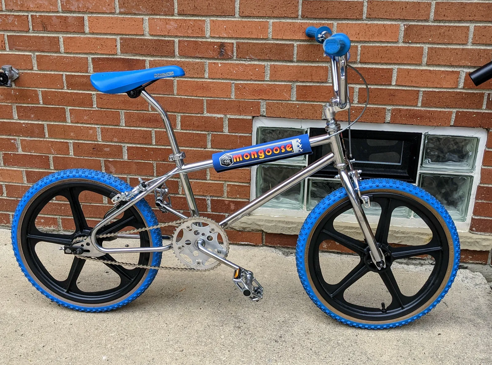 Finished blue 1985 Mongoose Californian against brick.