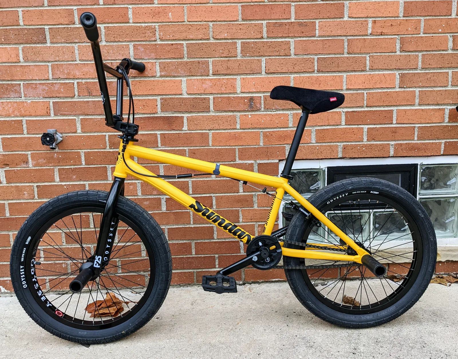 First outdoor side profile of the yellow Sunday Soundwave against a brick wall.