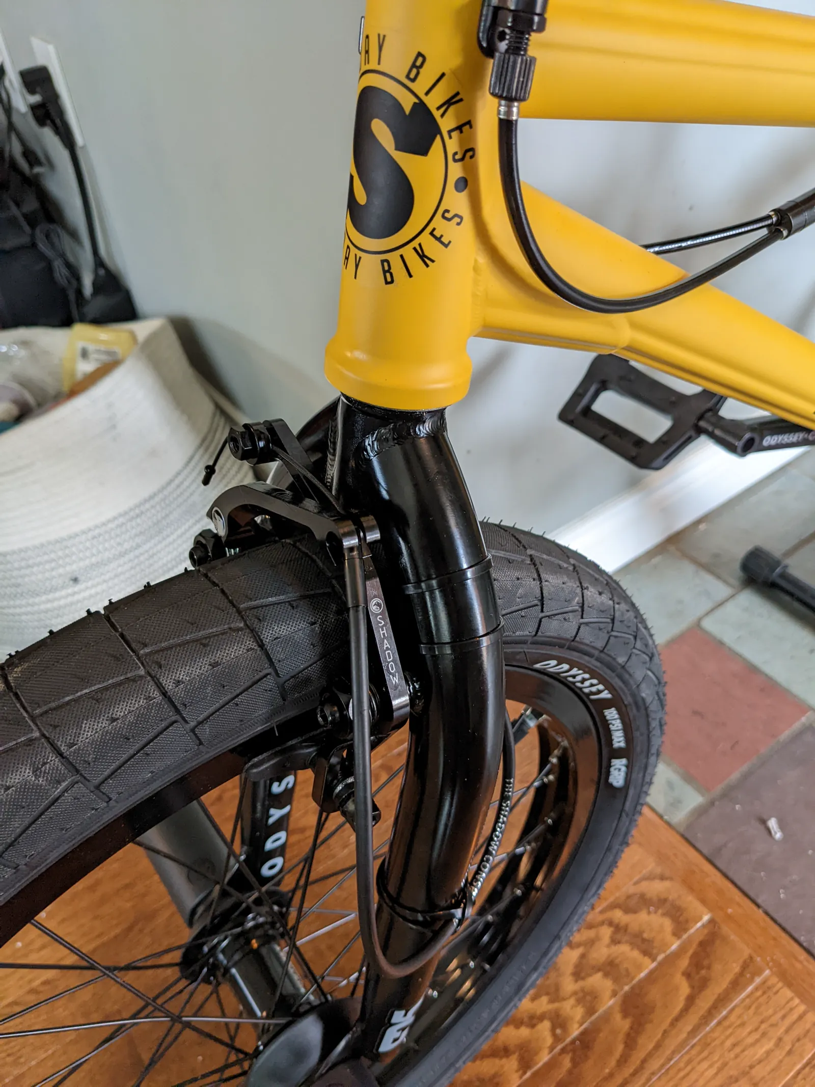 Close front-quarter view of the yellow Sunday headtube, black fork, front wheel, and cable routing.