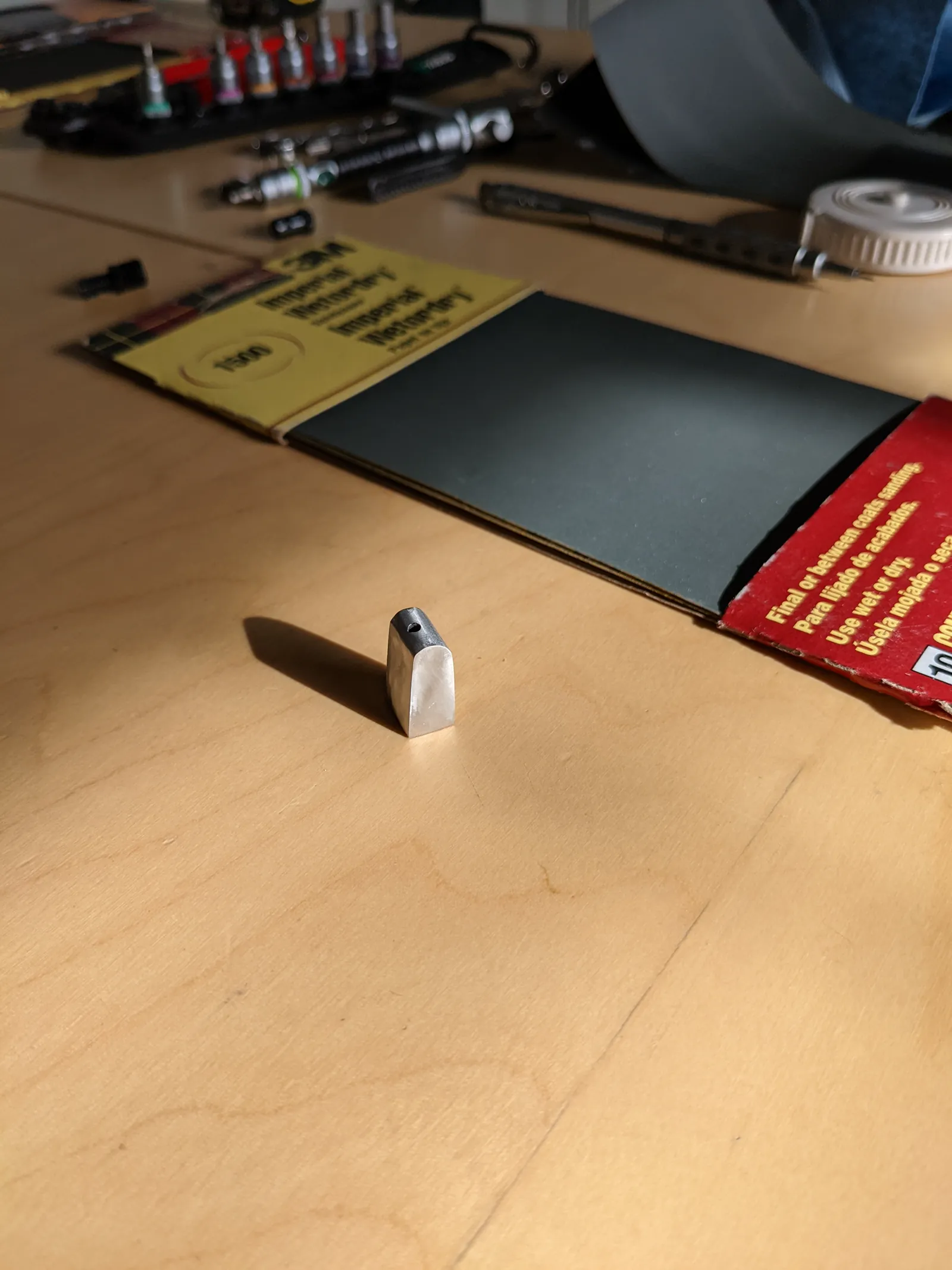 Small metal part staged on masking paper from a second angle.
