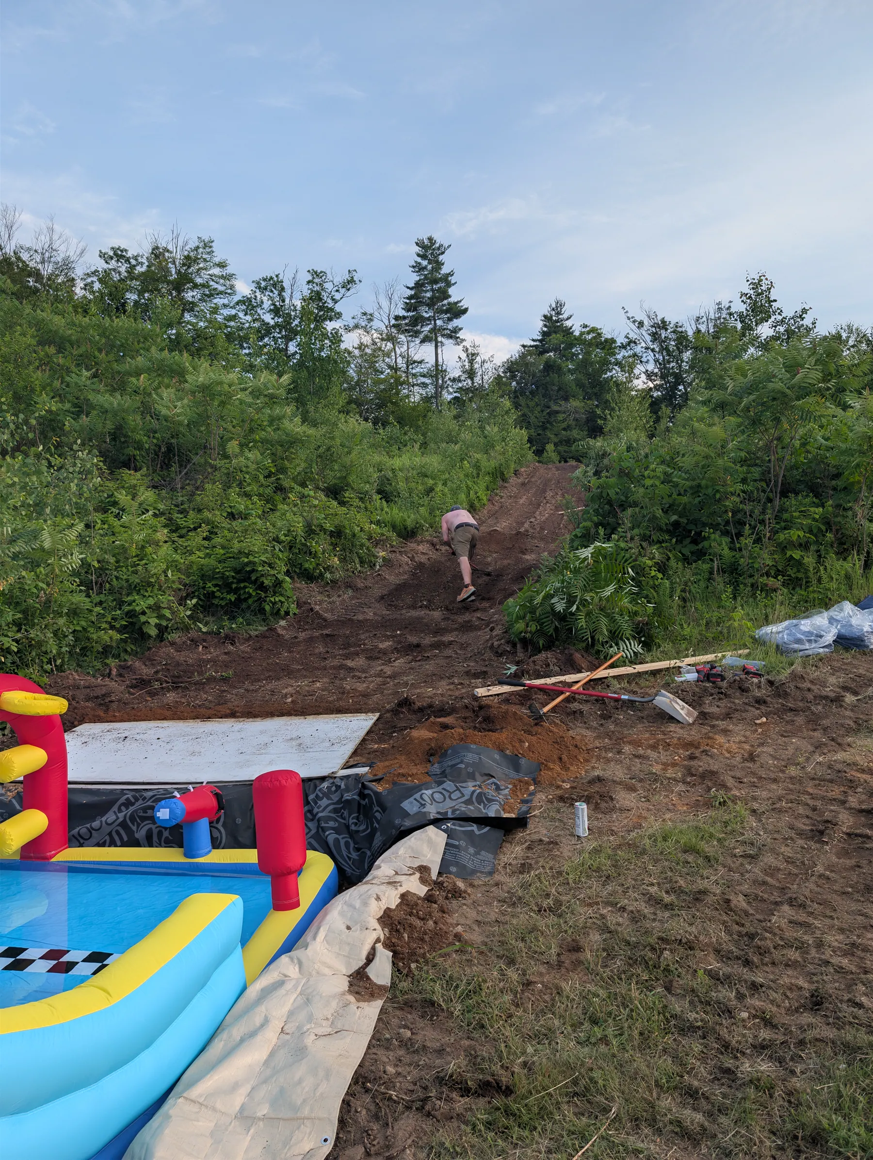 Person hand raking the dirt slide corridor uphill from the partially recessed water castle.
