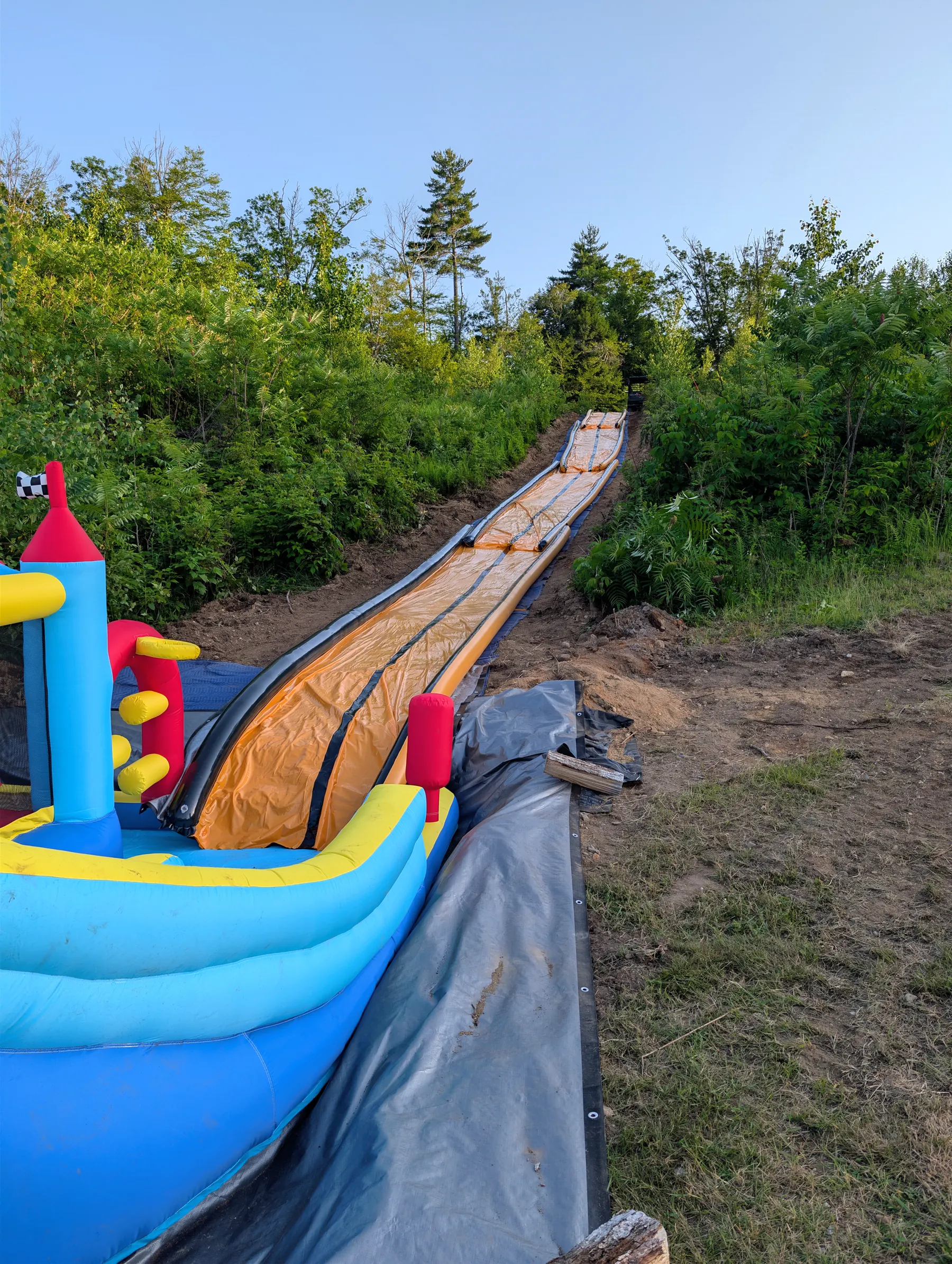 Orange slide entering the colorful bounce castle at the recessed backyard landing.