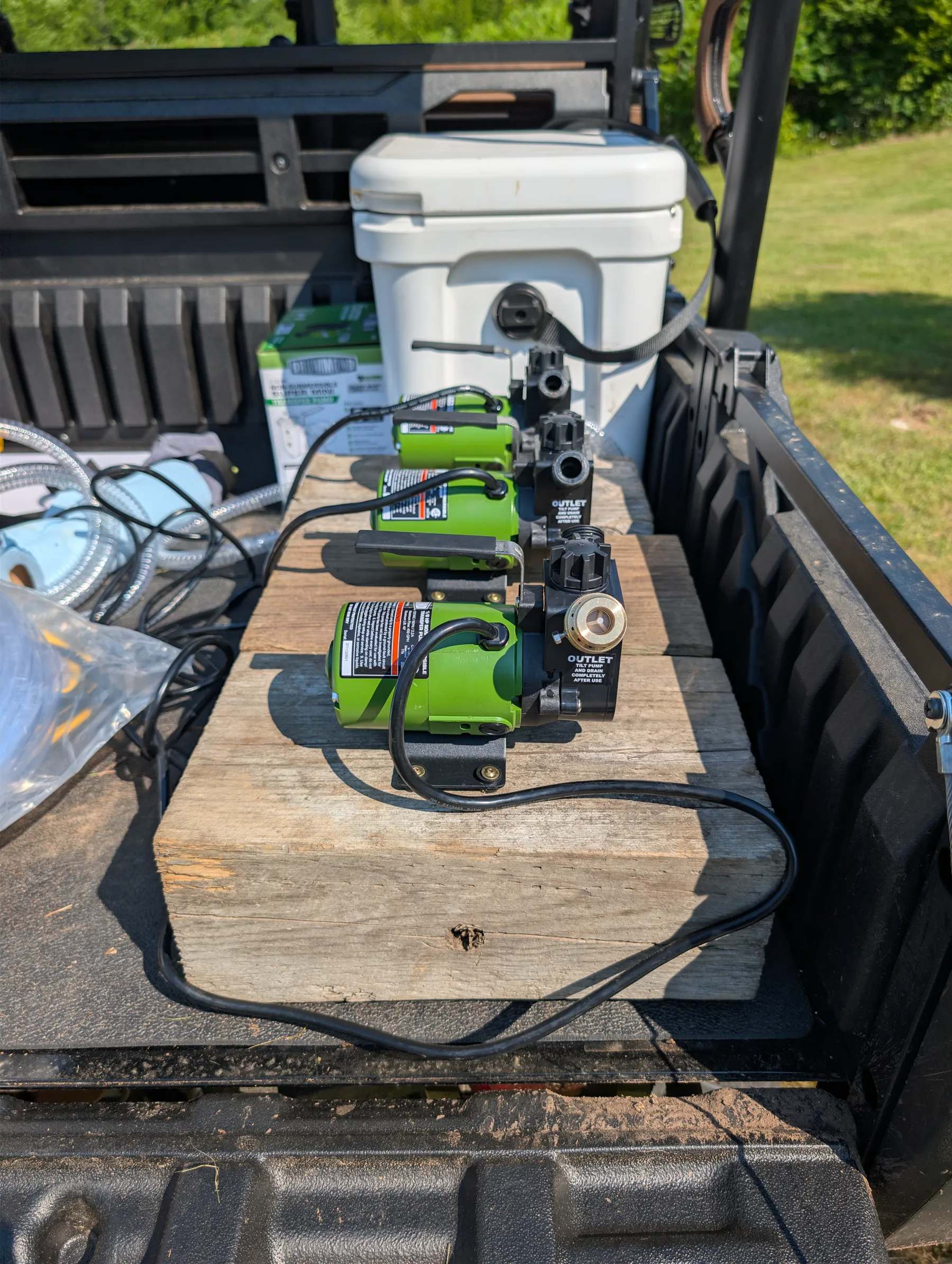 Three green transfer pumps arranged together on a wooden base.