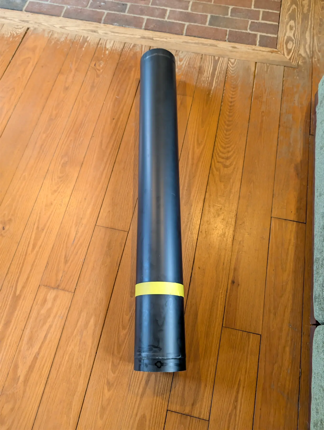 Long black straight connector-pipe section laid out for fitting.