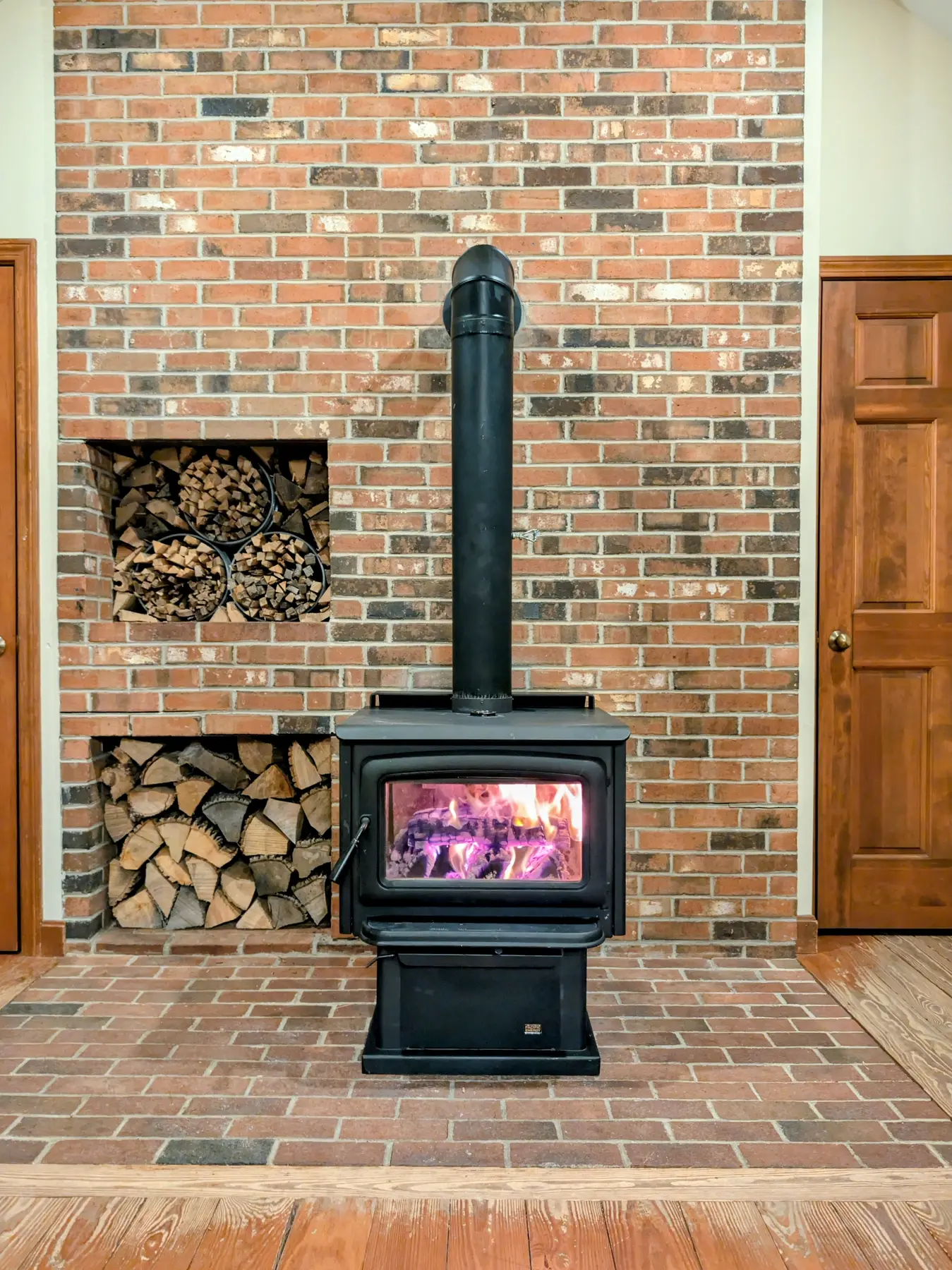 Front view of the completed Pacific Energy woodstove and connector pipe with the first fire burning behind the glass.