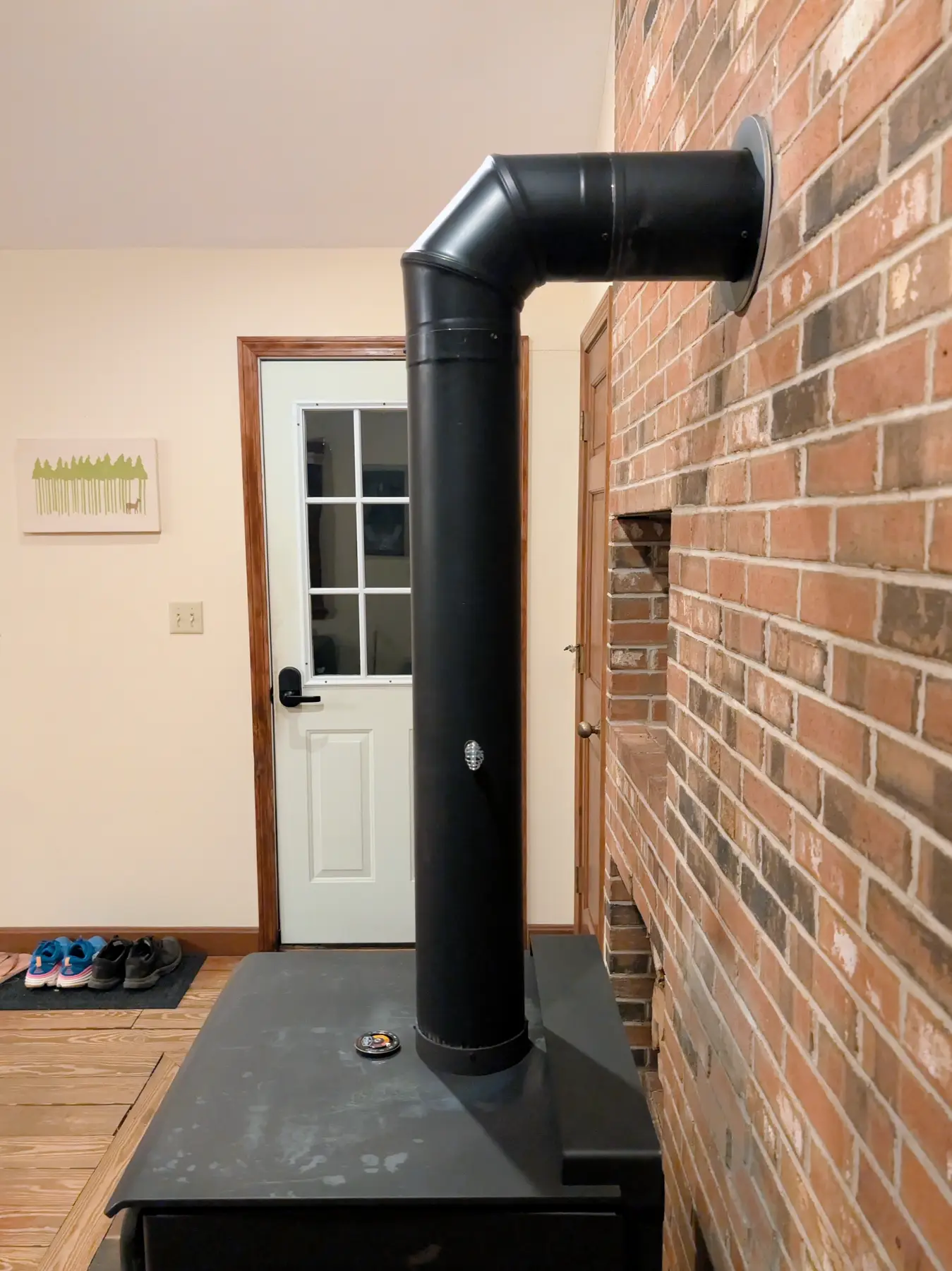 Side view of the black stove connector rising vertically and turning through an elbow into the brick wall.