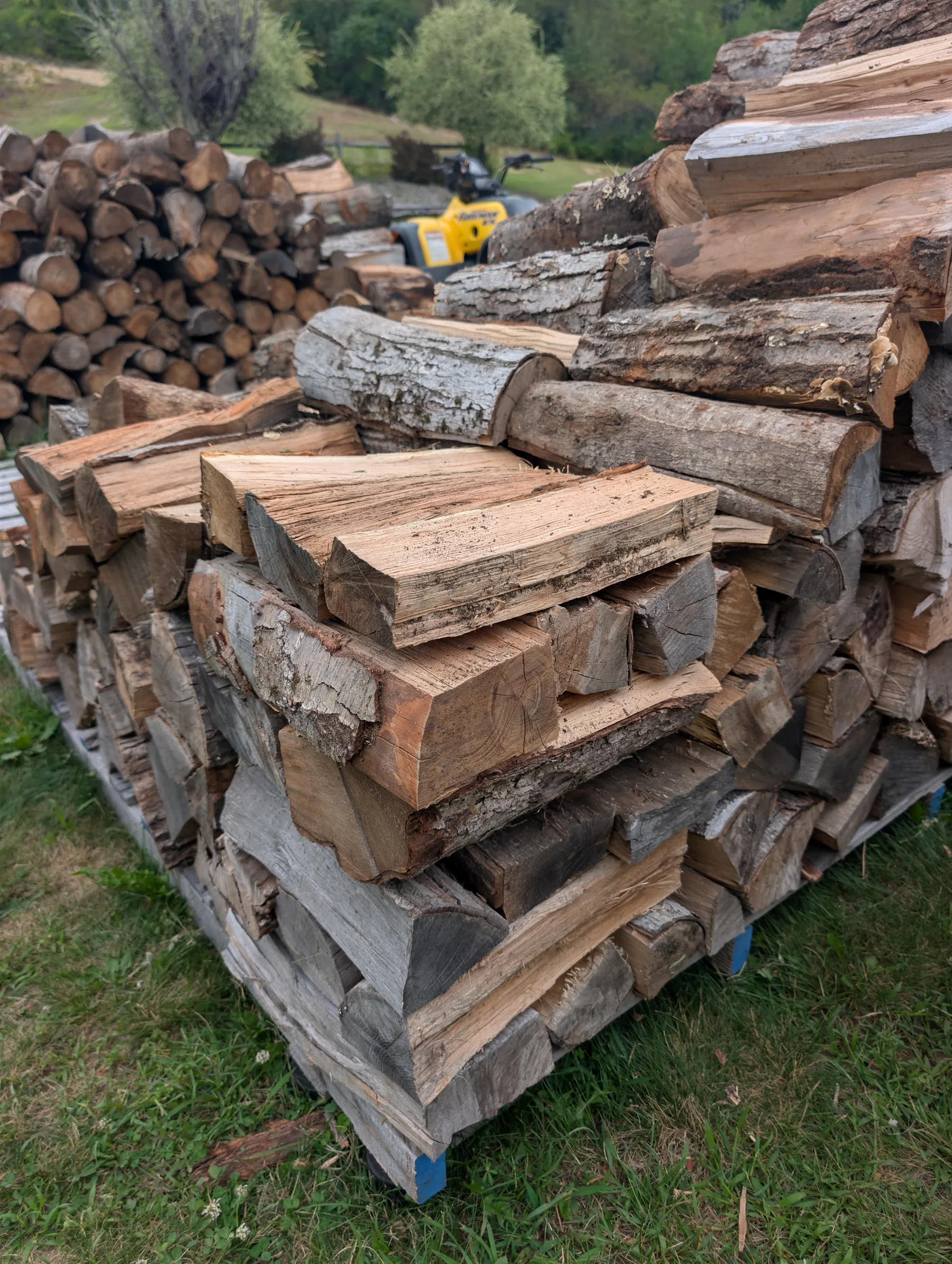 Close view of an interlocked corner tower built from firewood pieces with broad, nearly planar faces.