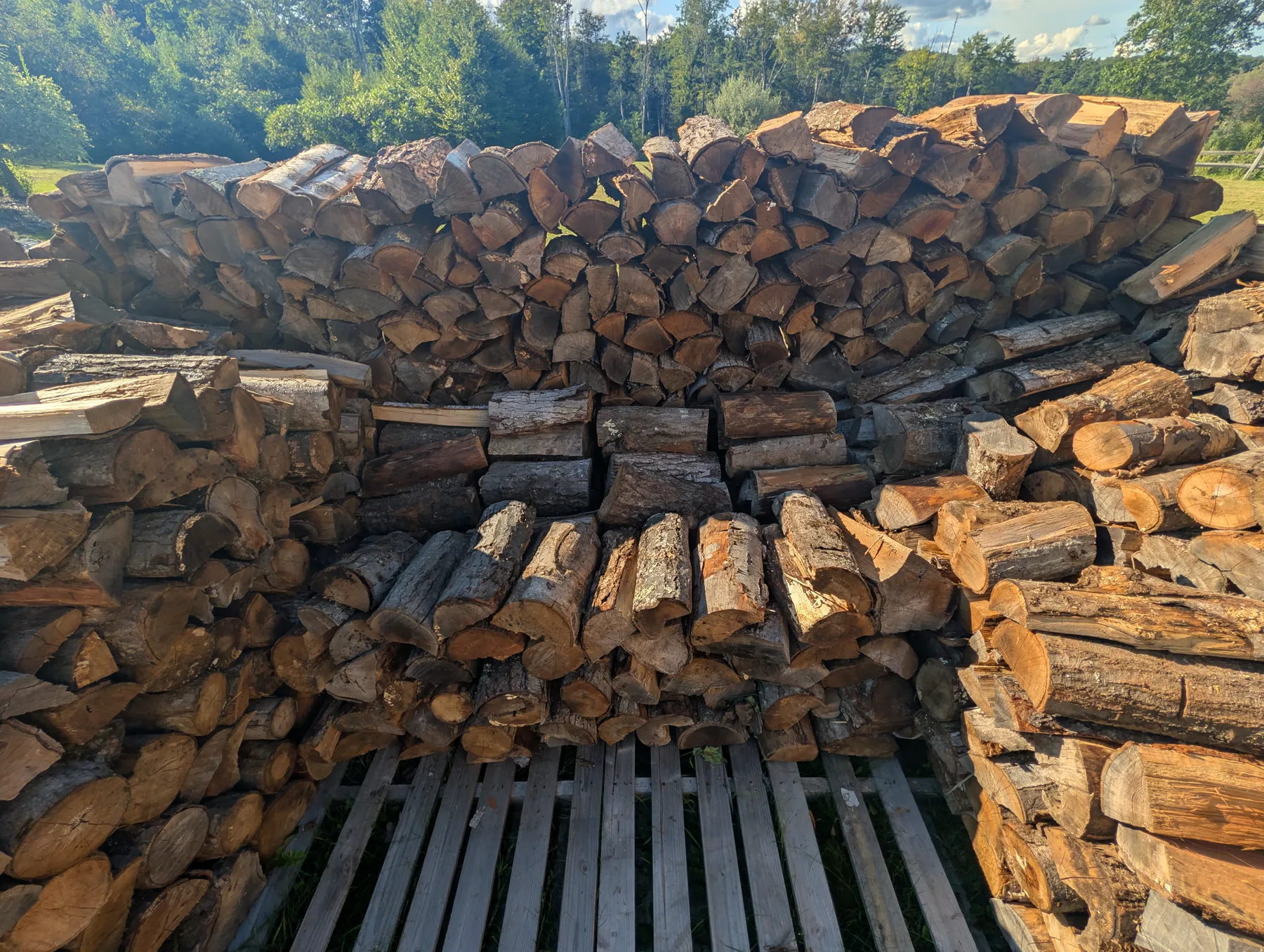 View into the unfinished stack showing parallel interior firewood, a short center row made from perpendicular pieces, and outer walls rising around it.