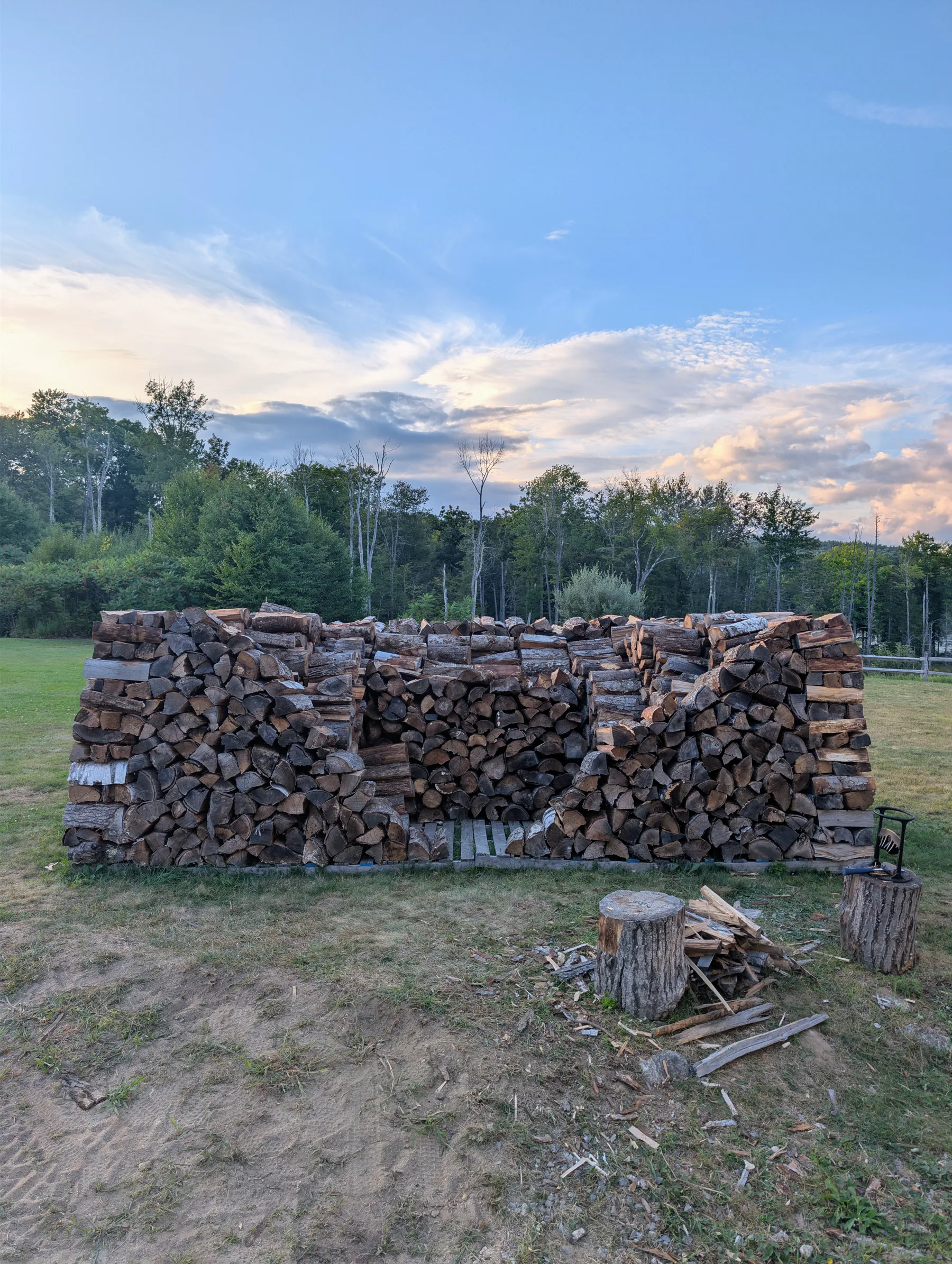 View of the rectangular firewood build with inward-tapered walls, tall corner towers, and the center still accessible.