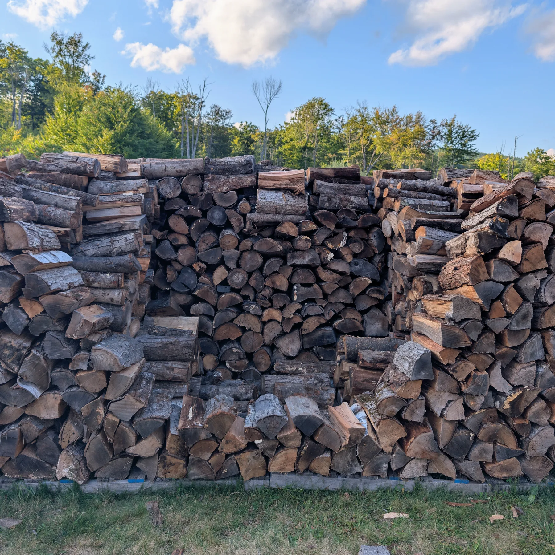 Close view of the stack with firewood set across the lower part of the final wall opening while the upper center remains accessible.