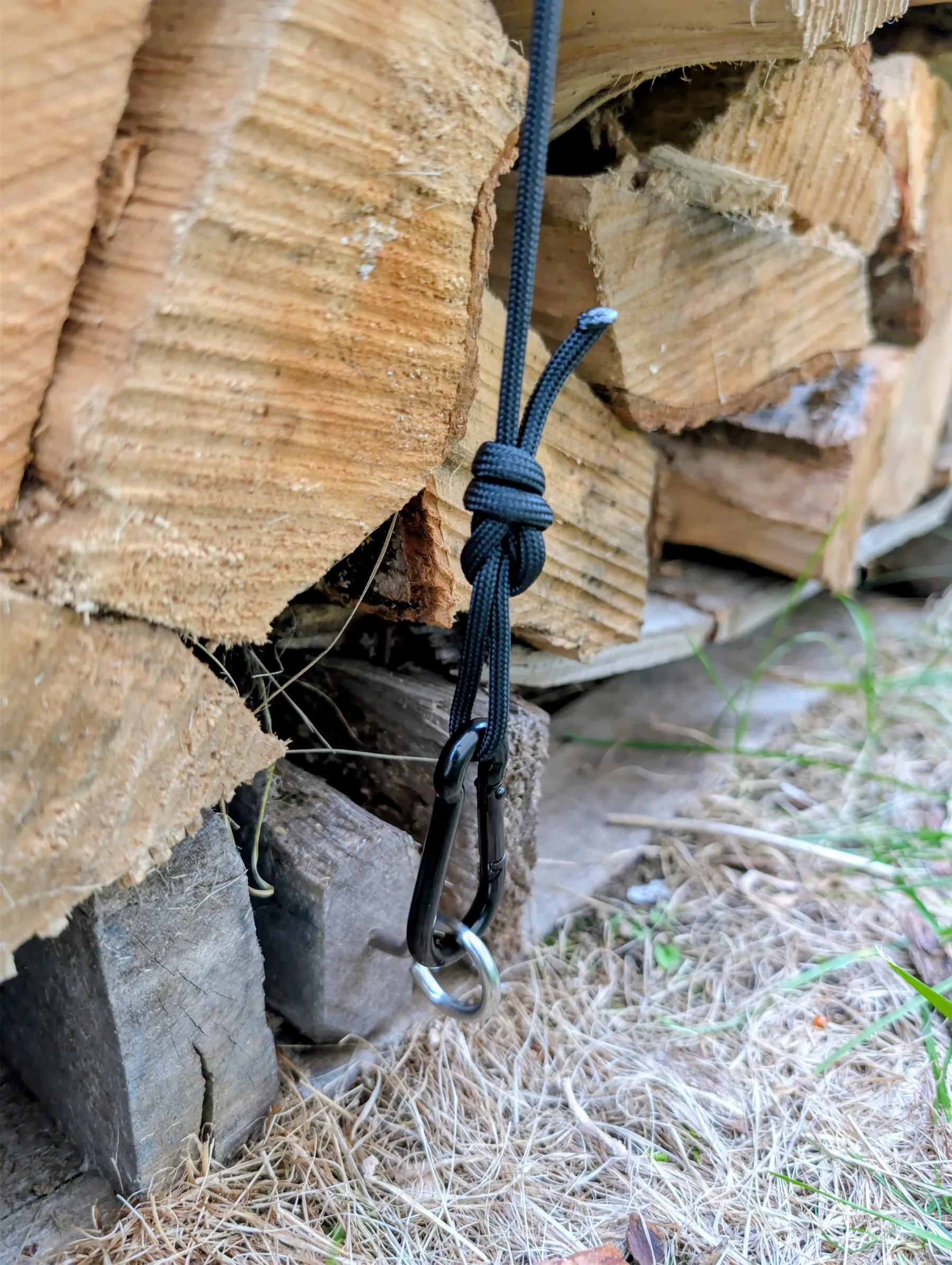 Close view of an adjustable paracord loop attached by a small black steel carabiner to a silver eye bolt in the pallet.