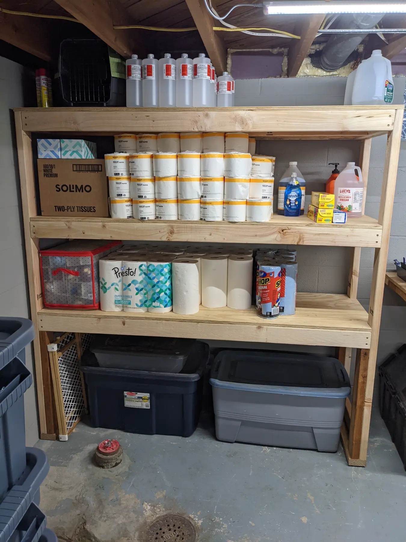 First basement supply shelf fully stocked with household supplies and larger containers below.