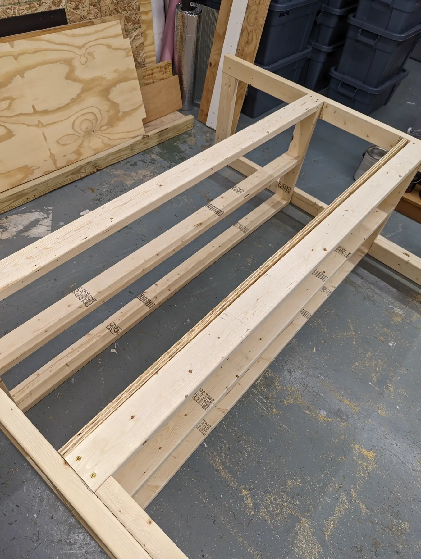 Long workshop shelf rails joined to the first end frame during assembly.