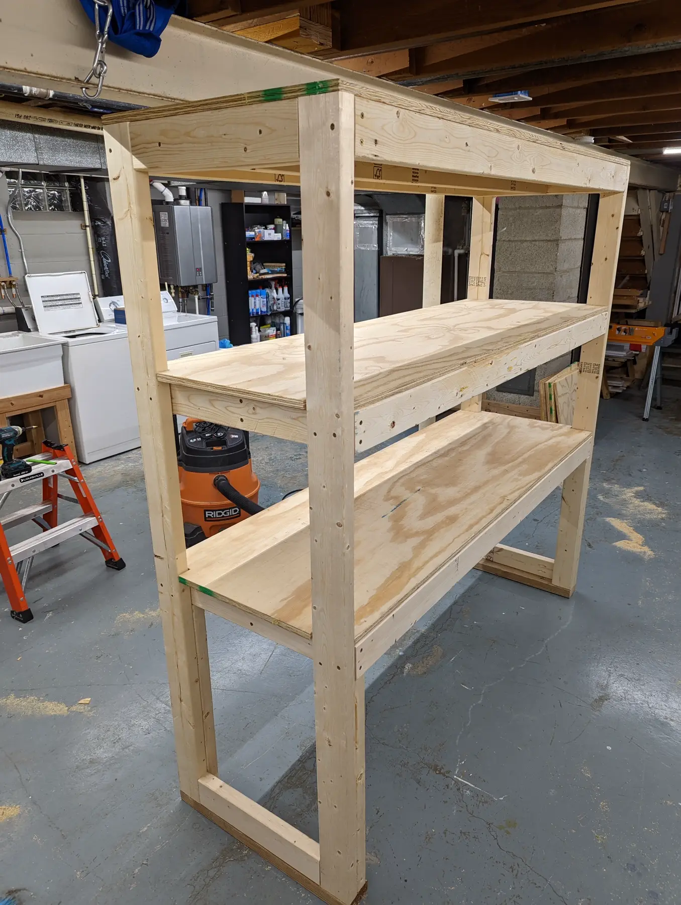 Freestanding workshop shelf frame with three long open levels.