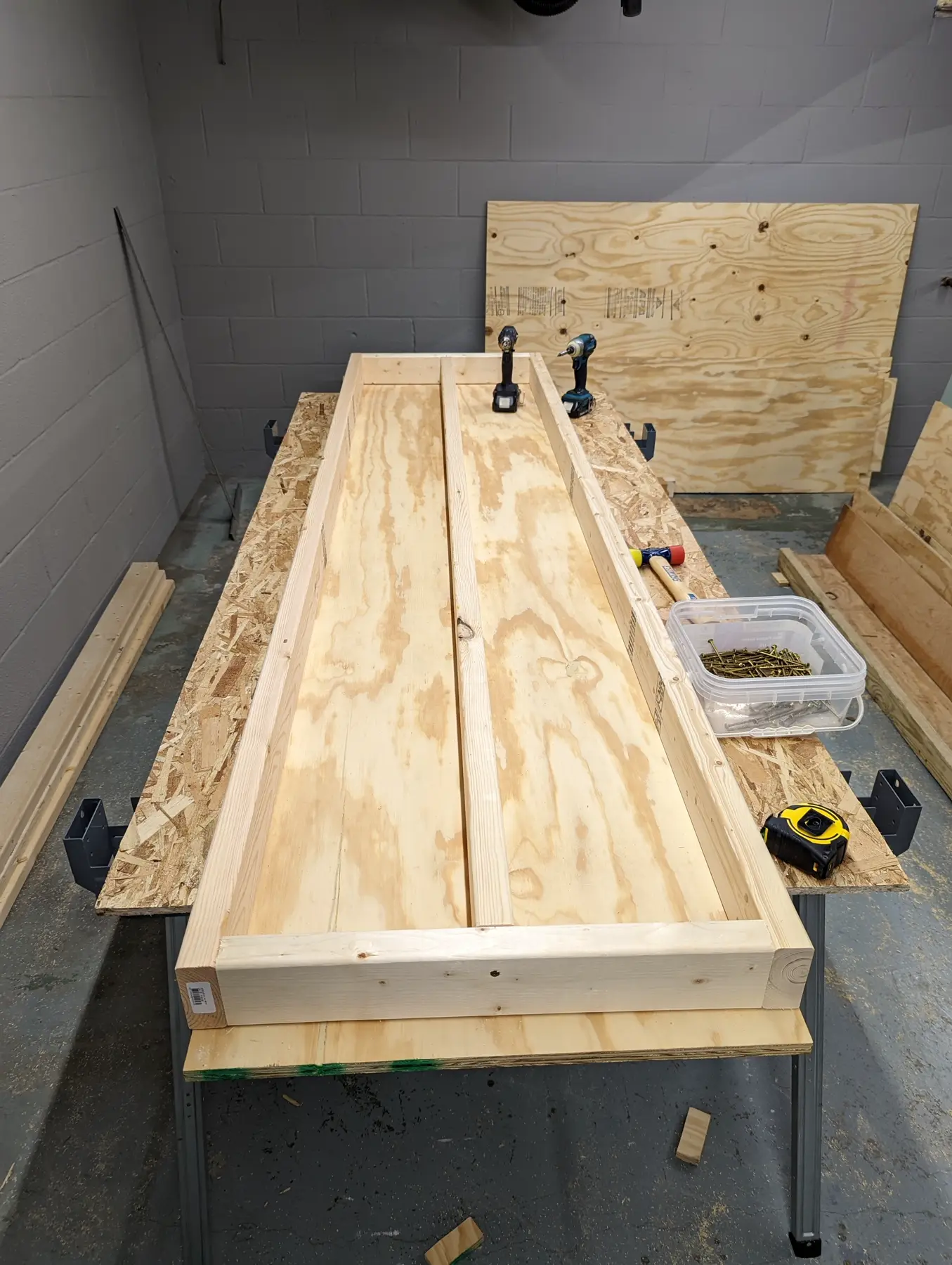 Long wood shelf decks prepared for installation on the workshop frame.